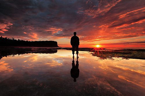 A person standing on the beach at sunset, embracing the beauty of nature. Love Your Work.