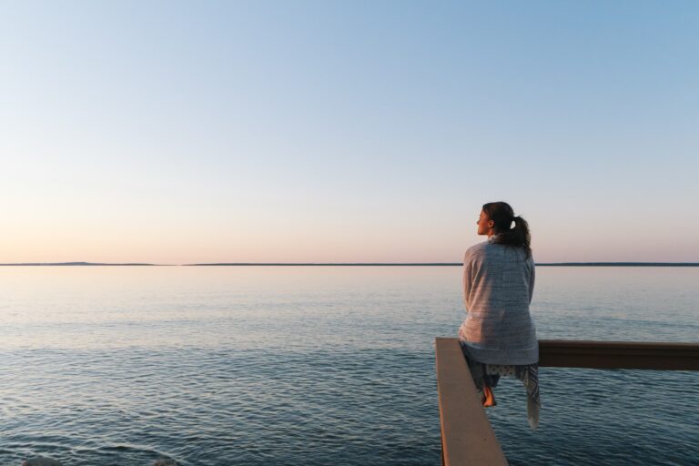 a woman sitting on and looking over the vast ocean, understanding and embrace your limitations