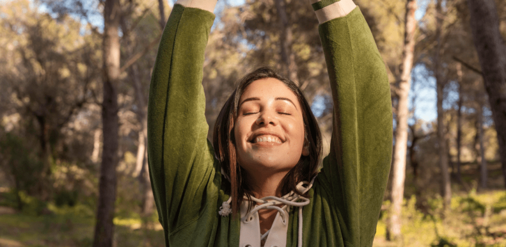 A woman with strength-based leadership, holding her hands up in the air.